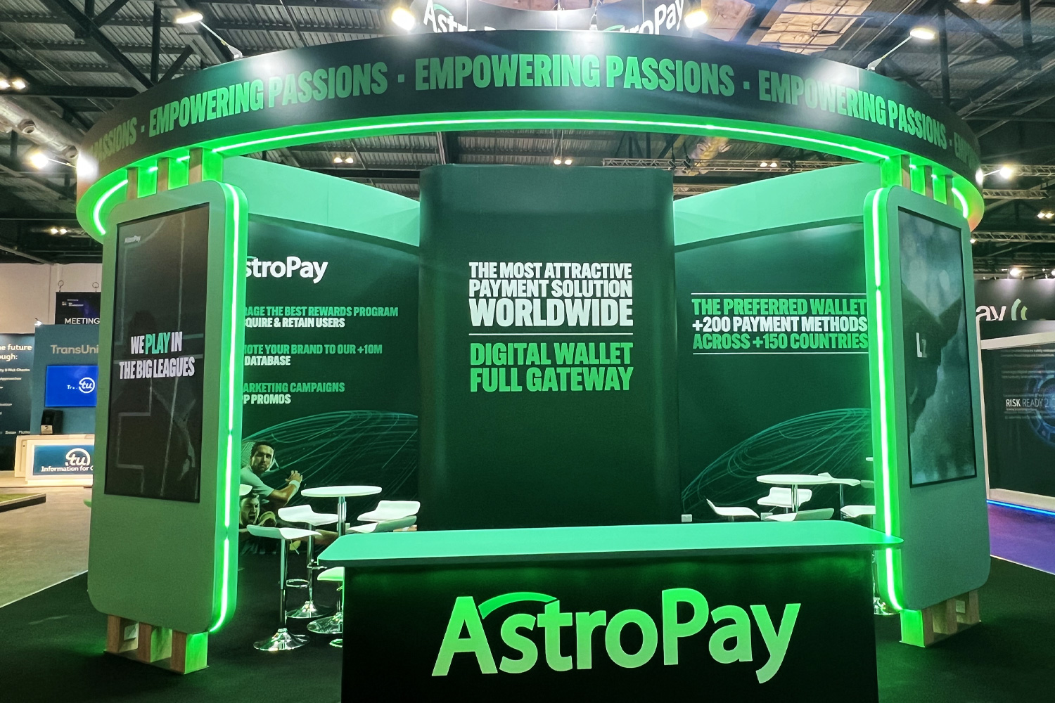 Modern curved exhibition wall with backlit branding and integrated shelving, designed for maximum visibility at live events