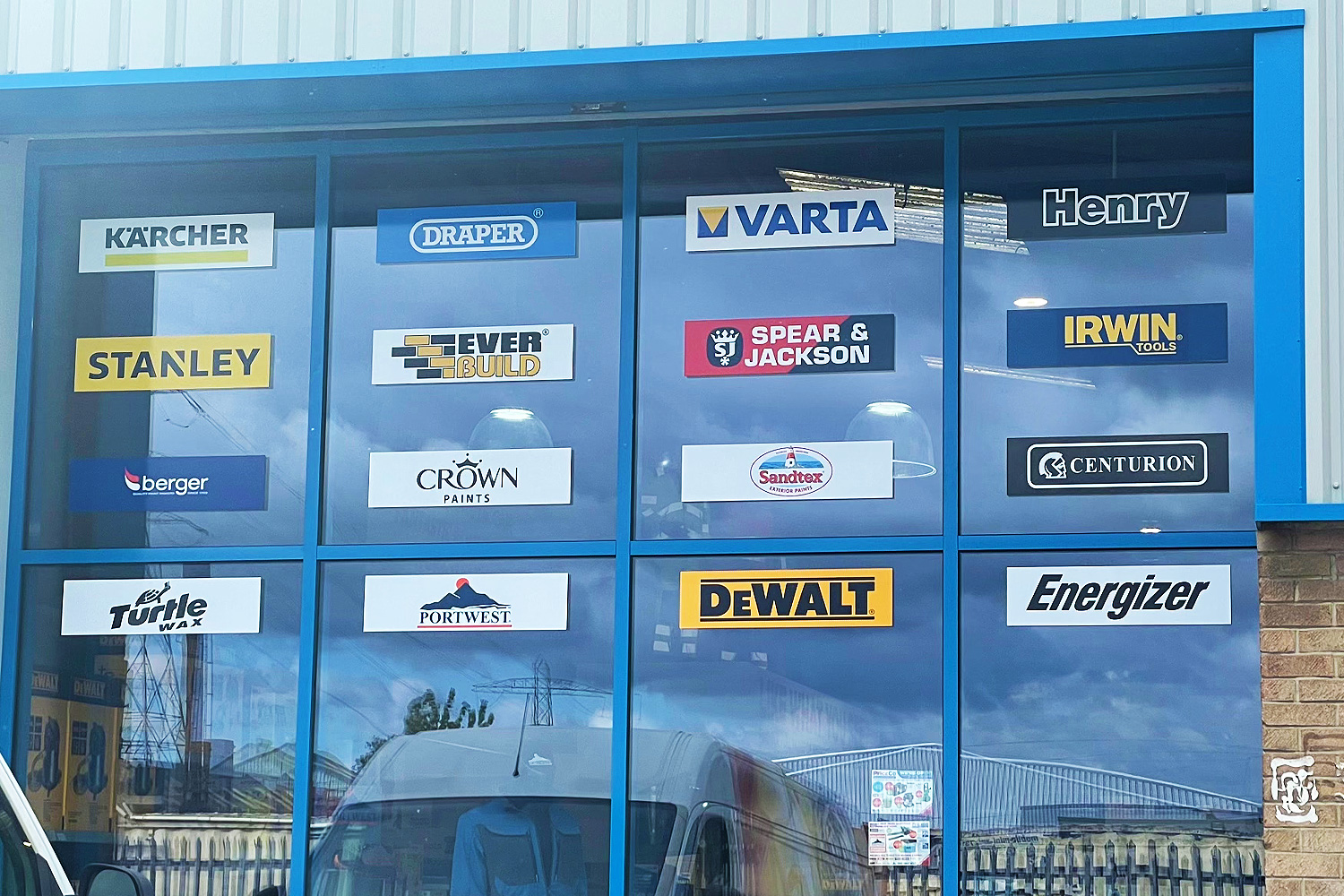 Window display featuring logos of top tool and paint brands including Stanley, Draper, Varta, DeWalt, Crown Paints, Energizer, and Karcher