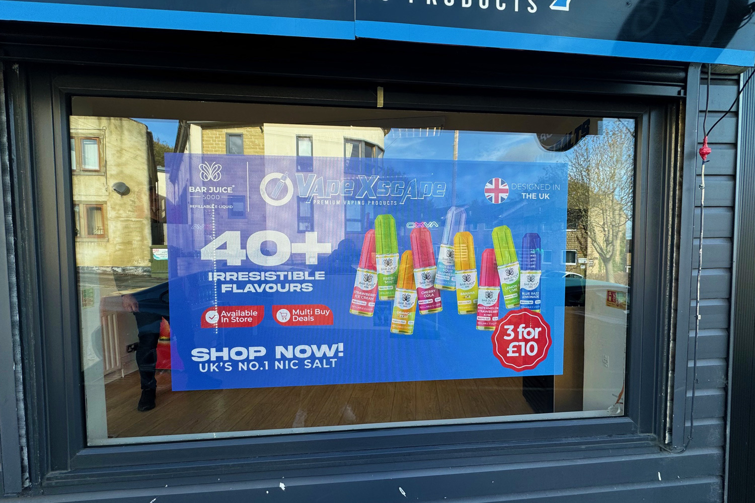 Bright and colourful window poster advertising VapeXscape with Bar Juice products, promotional pricing, and UK-designed branding