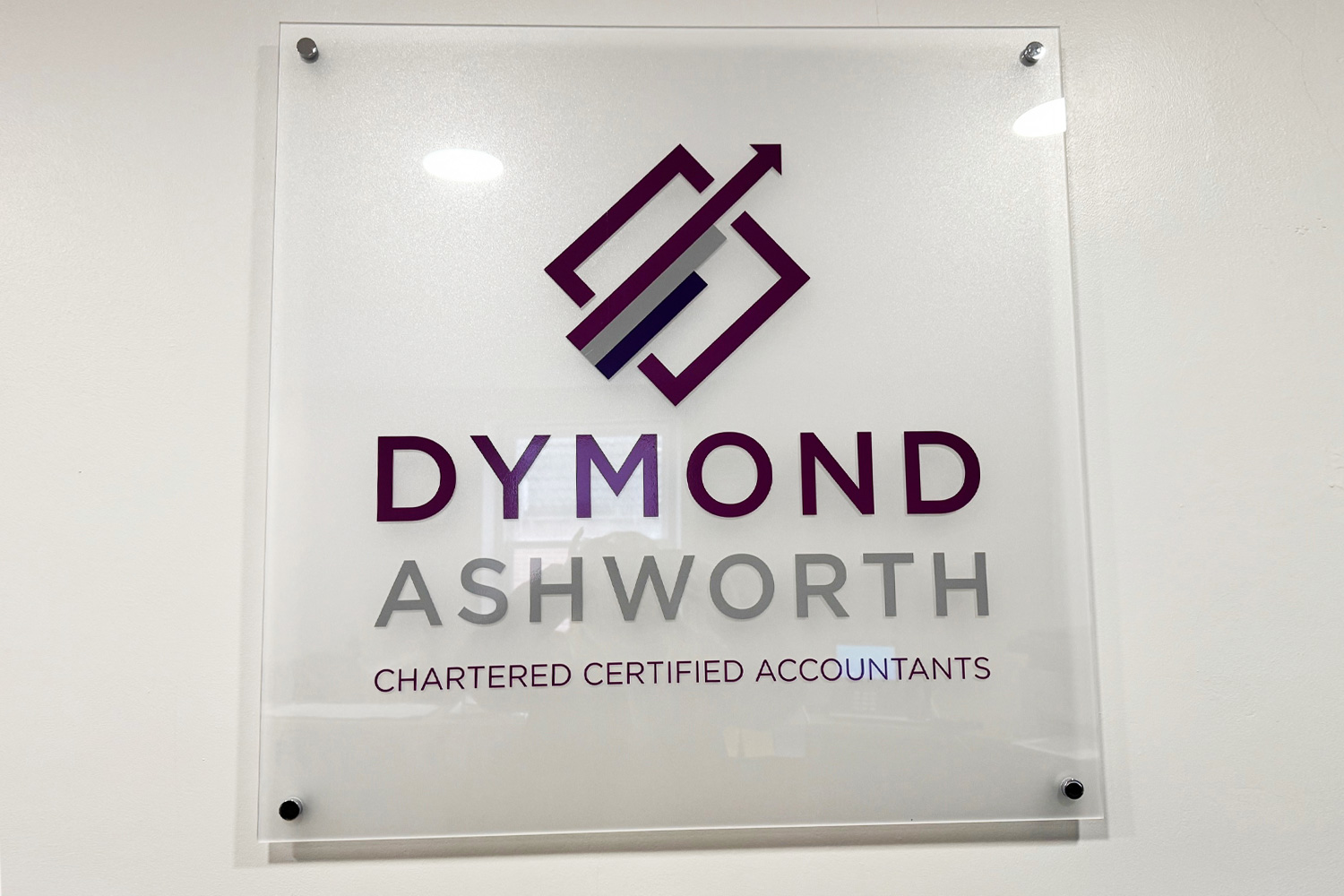 Frosted acrylic wall sign with raised lettering for Dymond Ashworth Accountants, professionally installed on an interior wall
